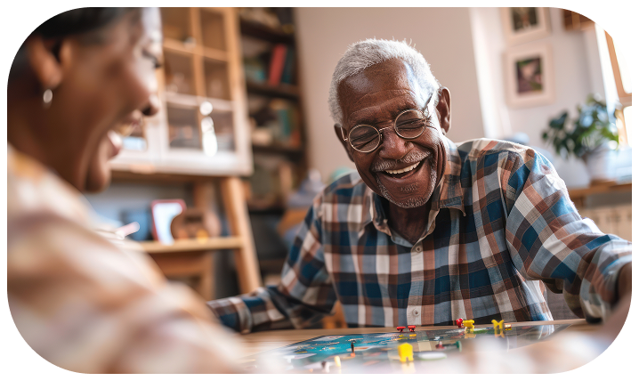 senior-man-laughing-while-playing-board-game-with-his-caregiver
